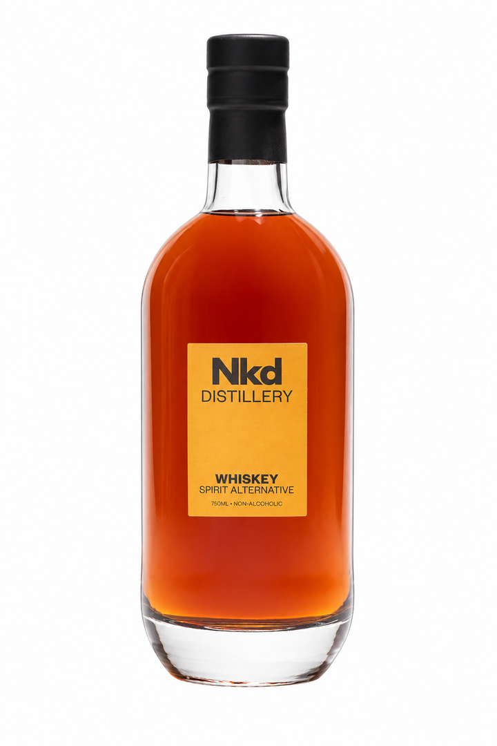 A bottle of Nkd Distillery Whiskey Spirit Alternative, featuring a clear glass bottle filled with amber-colored liquid, a black cap, and a yellow label on a white background.
